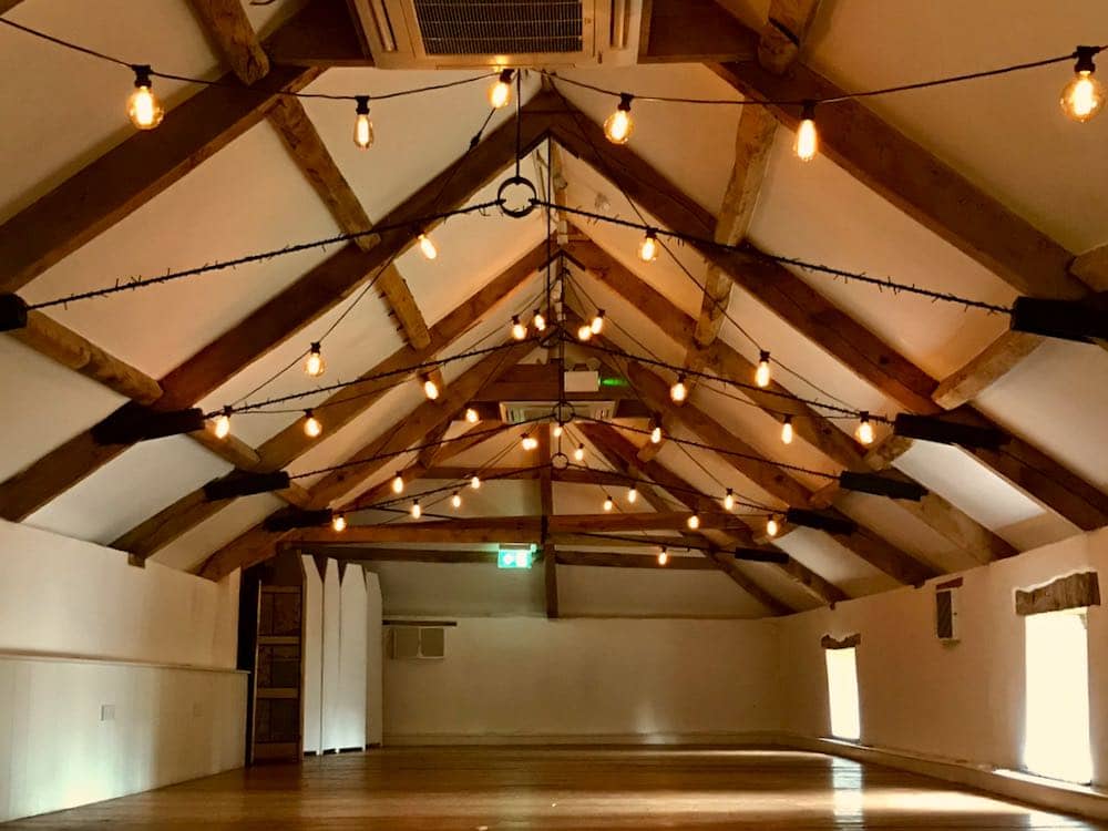 Interior, white walled attic barn with wooden beams, large empty wooden floor, edison vintage style lights cover the ceiling