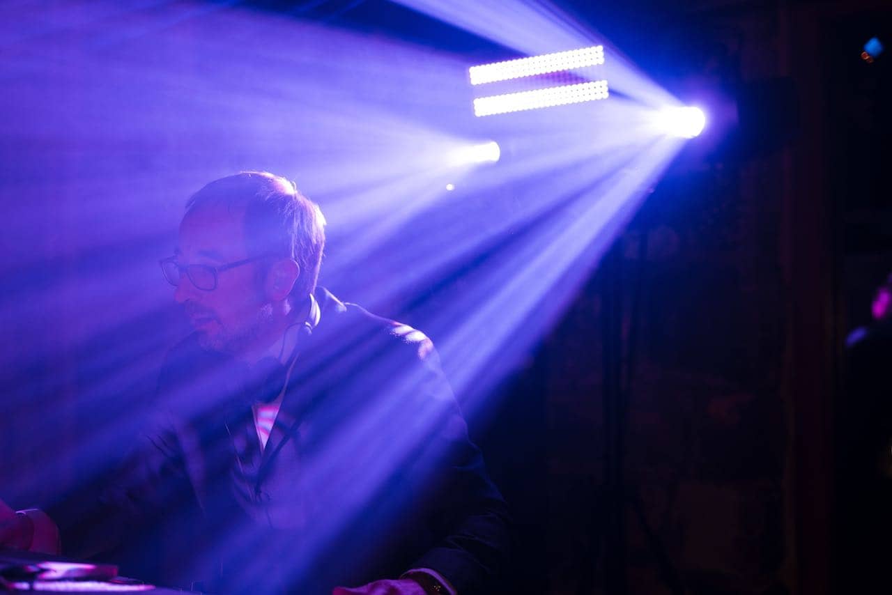 DJ Nige with violet lighting behind him.