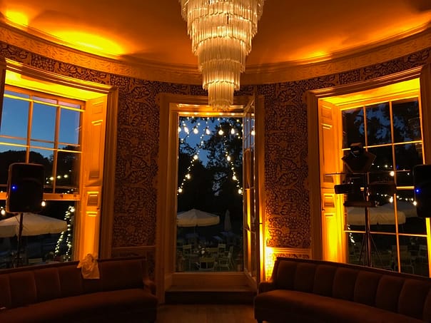 Amber Glow at Babington House Bar: The bar at Babington House is bathed in a warm amber glow, courtesy of LED up-lighting. A captivating lighting canopy emanates from the center of the frame door, creating a stylish and inviting ambiance in this chic setting.